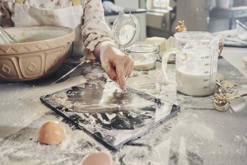 En Elkjøp-enhet som ligger på kjøkkenbenken dekket av bakeingredienser